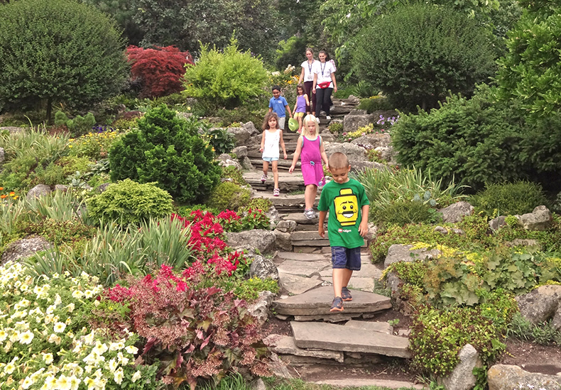 Summer camp staff and campers walking through a garden