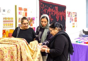 Women examining Phulkari embroidery with Rafia Shafiq