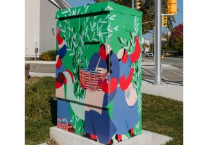 Traffic signal cabinet box wrap design depicts women harvesting olives in a grove.