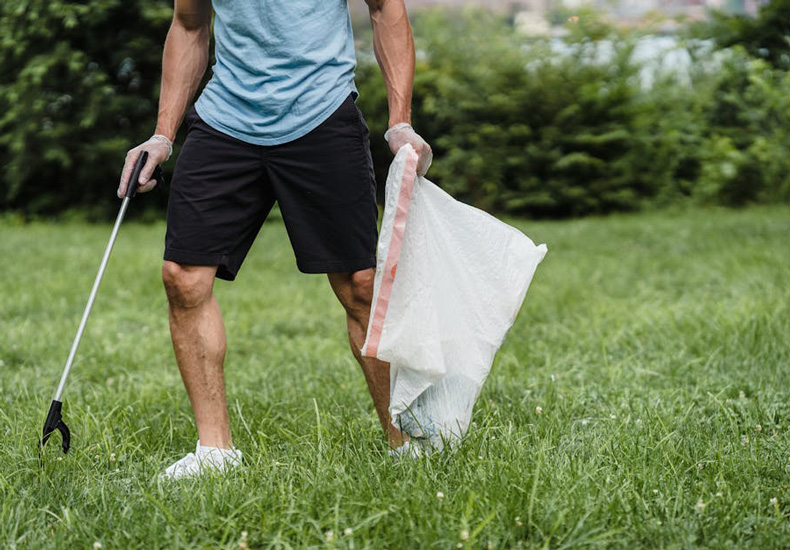 A person picking up litter from the grass