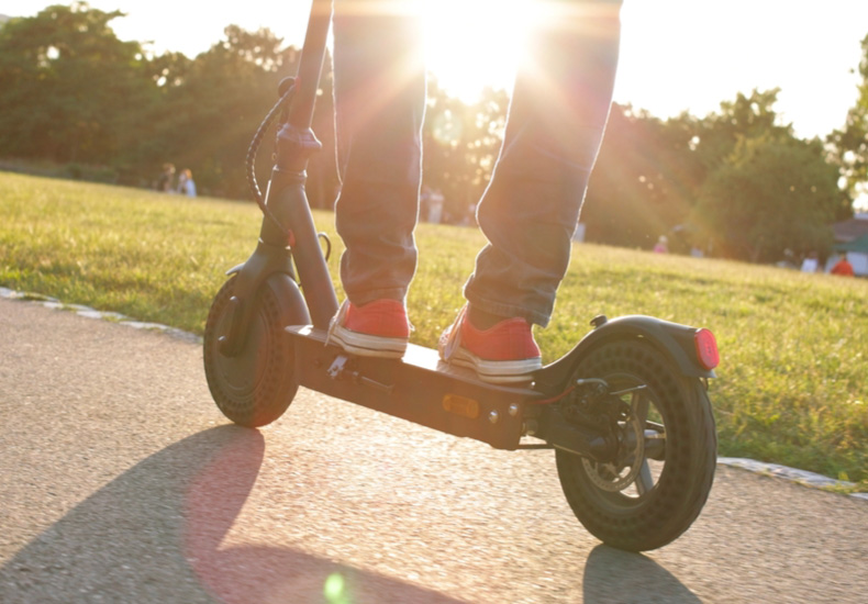 Close up of a person wearing red sneakers riding an e-scooter