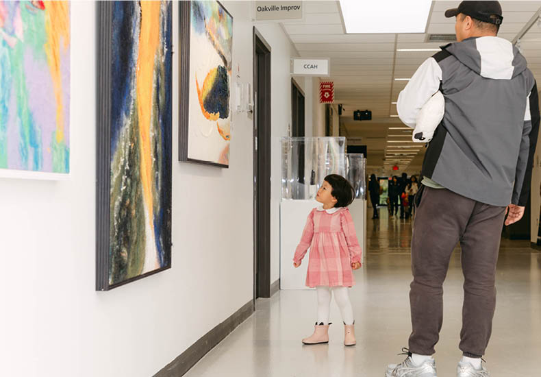 Parent and child viewing Fibre artworks on display for World of Threads Festival.