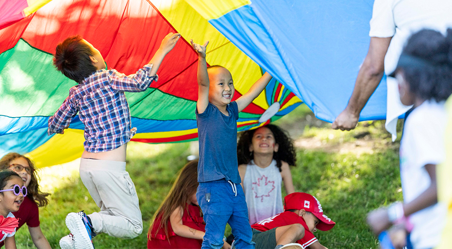 Children playing under a colourful parachute Children playing under a colourful parachute